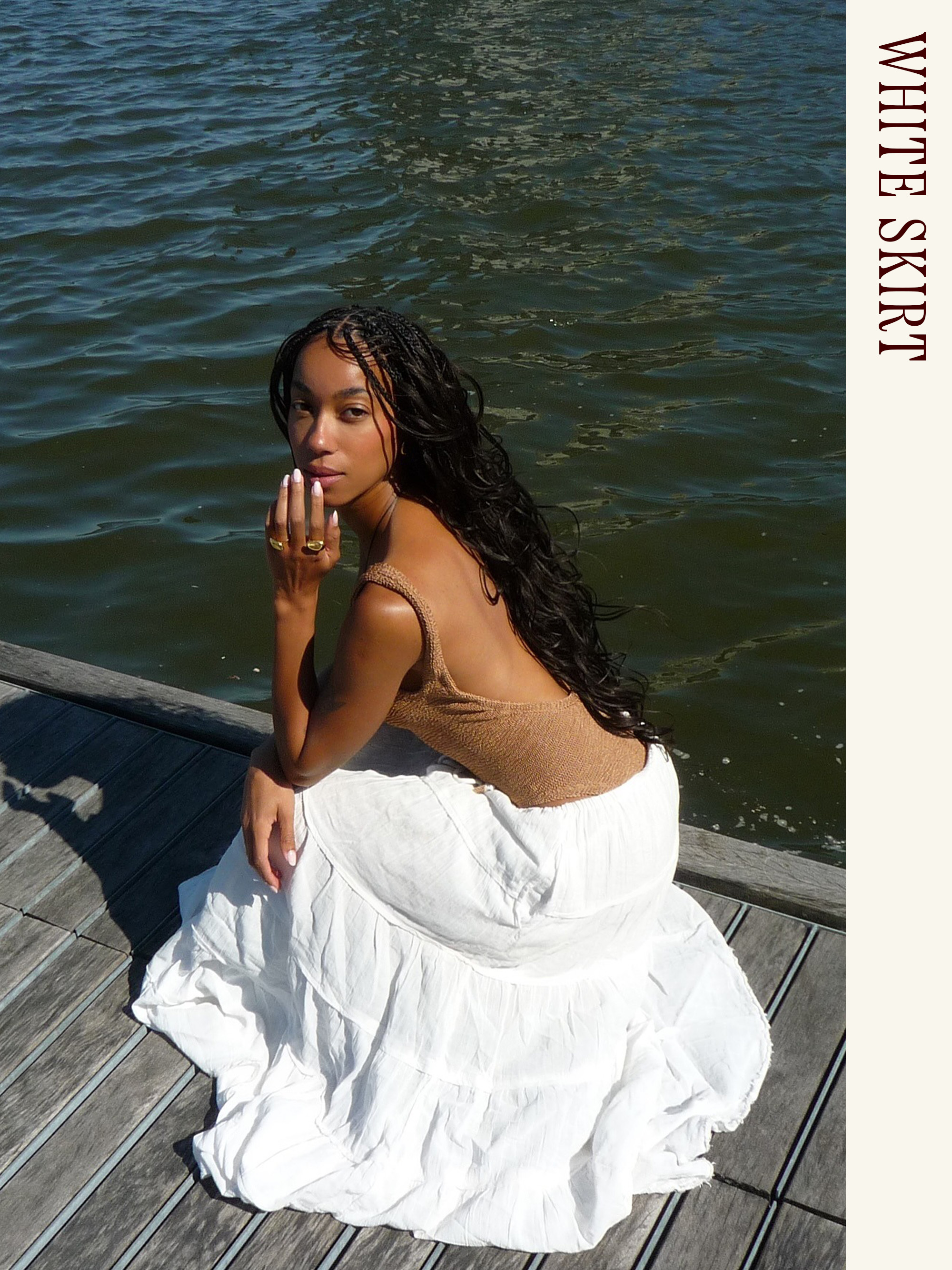 Influencer wearing a swimsuit and long white skirt.