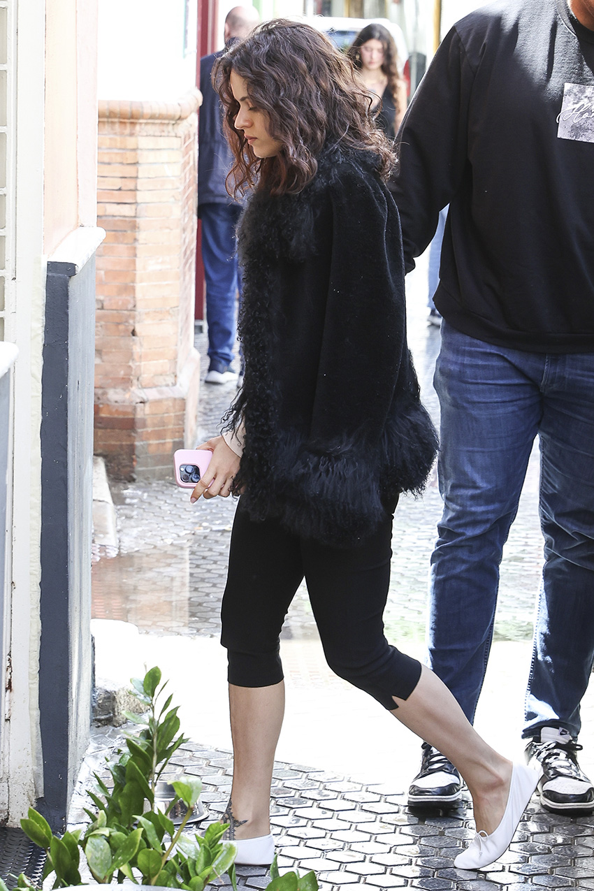 Rosalia wearing a fur-trimmed jacket with black capri pants and white ballet flats.