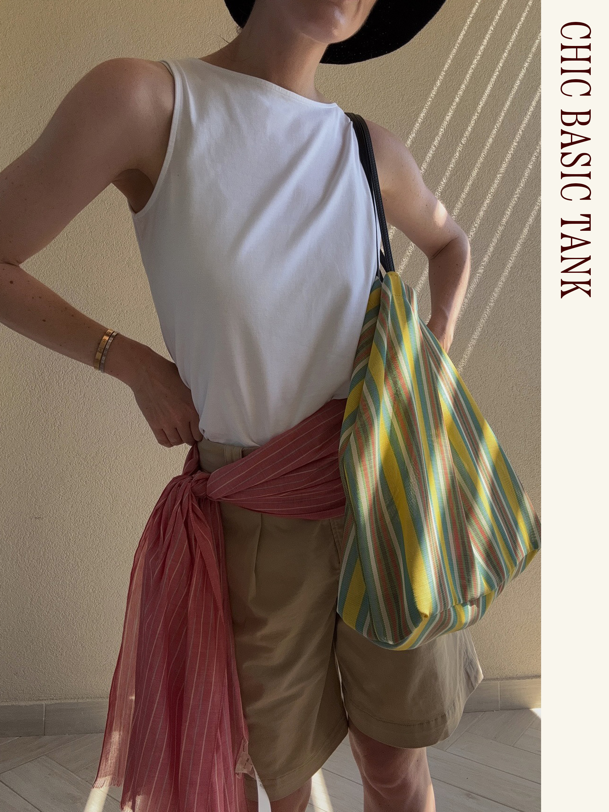 Influencer wearing a white tank, khaki shorts, scarf belt, and The Row Barn Tote.